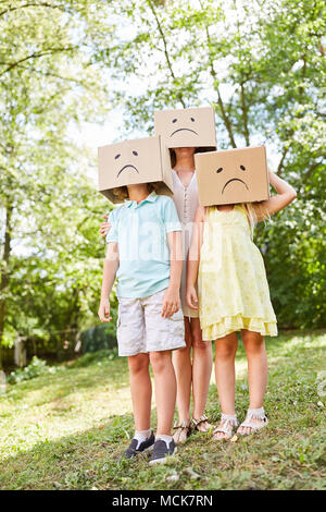Familie mit Kindern steht im Garten in Kartons mit traurigen Gesichtern Stockfoto
