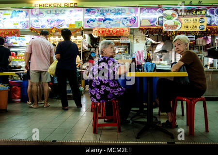Singapur - Januar 29, 2014: Zwei alte Frauen sitzen auf einem Tisch in der Hawker Center, wo Singaporean Menschen die Vielfalt der preiswertes Essen genießen. Stockfoto