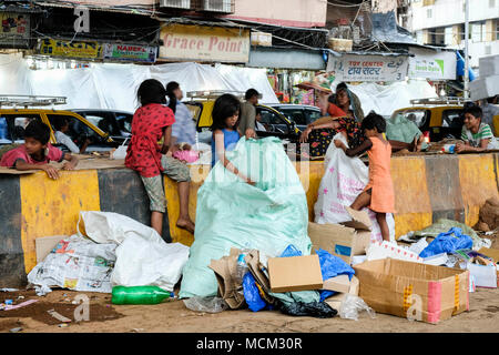 Straßenkinder arbeiten beim Sammeln von Pappe und Müll in der Innenstadt von Mumbai. Viel Verkehr hinter dem Hotel, Schild mit der Aufschrift „Grace Point“, Mumbai, Indien Stockfoto