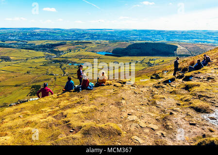 Wanderer ruht gerade unterhalb des Gipfels des Pendle Hill, auf der Suche nach Nelson und Brierfield, mit dem West Pennine Moors am Horizont Stockfoto