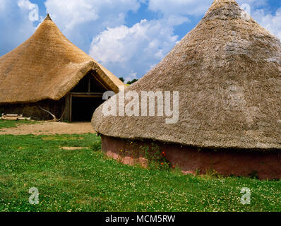 Die große Roundhouse (hinten L) & die Moel y Gaer Haus Butser Ancient Farm, Hampshire, UK. Archäologische Rekonstruktionen auf Ausgrabungen. Stockfoto