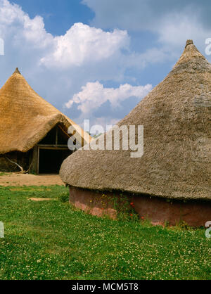 Die große Roundhouse (hinten L) & die Moel y Gaer Haus Butser Ancient Farm, Hampshire, UK. Archäologische Rekonstruktionen auf Ausgrabungen. Stockfoto