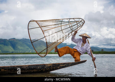 Fischer, die traditionelle Kleidung balancing im Ruderboot mit Angeln Warenkorb und Paddel, Shan Staat, Myanmar Stockfoto