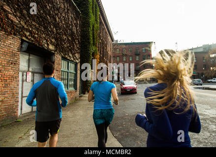 Ansicht der Rückseite des männlichen und weiblichen Läufer joggen in Street, Pioneer Square, Seattle, Washington State, USA Stockfoto