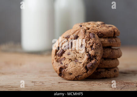 Ein Stapel von Cookies mit Milch Schokolade und zwei Flaschen Milch auf einen hölzernen Tisch. Stockfoto