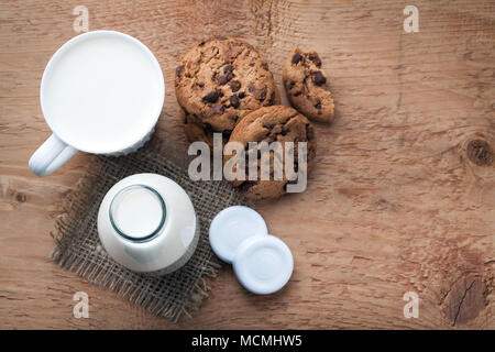 Zwei Flaschen Milch und Chocolate Chip Cookies auf dunklem Hintergrund mit kopieren. Ansicht von oben. Stockfoto