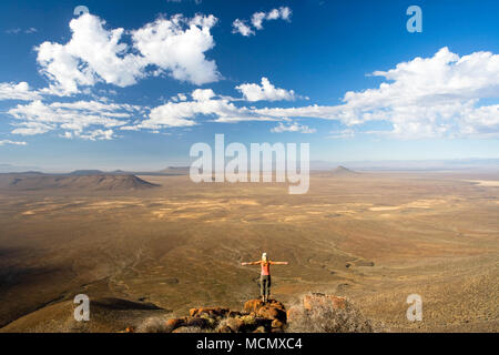 Eine Frau, die am Rande einer Klippe in der malerischen Landschaft der Tankwa Karoo, Western Cape, Südafrika einzutauchen Stockfoto