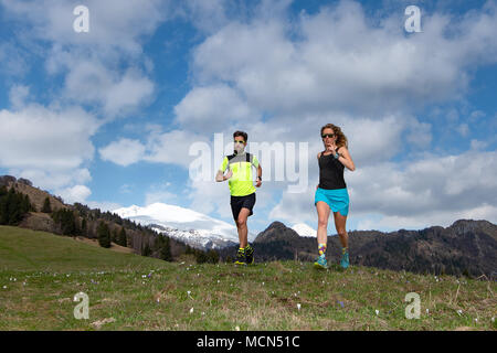 Paar von männlichen und weiblichen Athleten trainieren in den Bergen. Stockfoto
