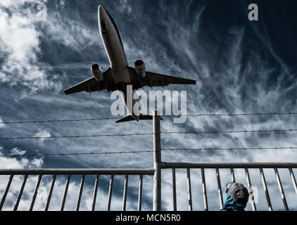 Frau, die Flugzeuge/Flugzeuge von hinter Stacheldraht-Perimeter, Grenzzaun beobachtet. Konzeptbild: Russland Ukraine-Konflikt, keine Flugzone, Flüchtlingskrise. Stockfoto