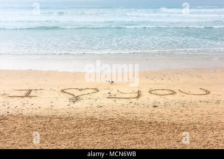 Ein kleiner Hund vorbei eine Nachricht Ich Liebe Dich in den Sand auf den Fistral Beach in Newquay Cornwall gezogen. Stockfoto