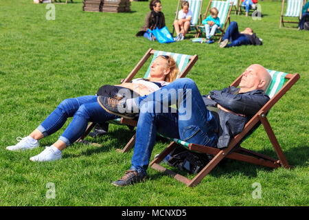 Green Park, London, 17. April 2018. Ein paar Snooze in ihren Liegestühlen auf der wärmste Tag des Jahres bis jetzt. Touristen und Einheimische, die das Londoner genießen Sie einen schönen, sonnigen Frühling in London mit blauen Himmel und warmen Temperaturen. Credit: Imageplotter Nachrichten und Sport/Alamy leben Nachrichten Stockfoto