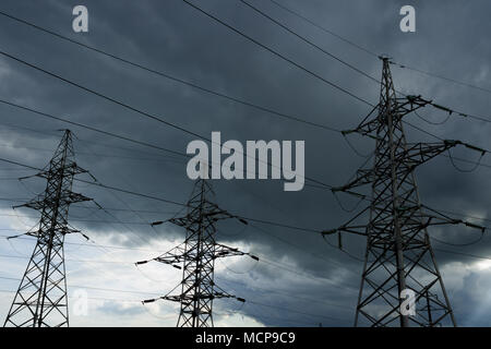 Hochspannung Strommasten gegen Gewitterwolke. Elektrische pole Leitungen und Drähte. Stockfoto