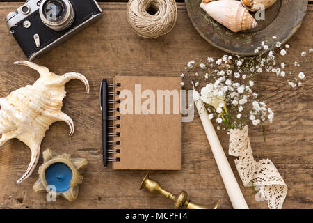 Rusitc Hochzeit Konzept. Zusammensetzung mit notepad durch kleine gypsophila Bouquet, Seashell, Kerzen, Kerzenhalter und Film Kamera umgeben zentriert. Stockfoto