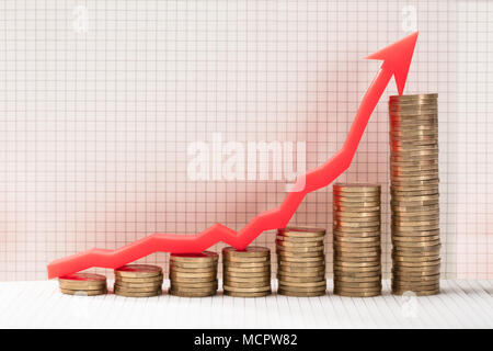 Nahaufnahme der steigenden goldenen Münzen mit rotem Pfeil zeigt nach oben Stockfoto