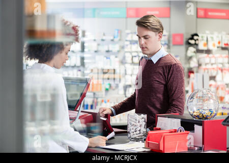 Junger Mann lächelnd beim Kauf eine nützliche Arzneimittel Stockfoto