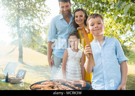 Portrait der glücklichen Familie mit zwei Kindern stehen im Freien in der Nähe von Grill Stockfoto