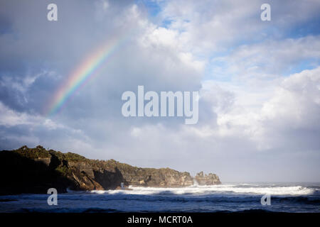 Ein Regenbogen zeigt über Dolomit Punkt bei Punakaiki an der Westküste der Südinsel von Neuseeland. Stockfoto