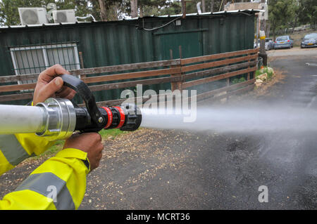 Feuerwehrmann in Schutzkleidung löscht ein Feuer als Bestandteil eine Brandbekämpfung Bohrer Stockfoto