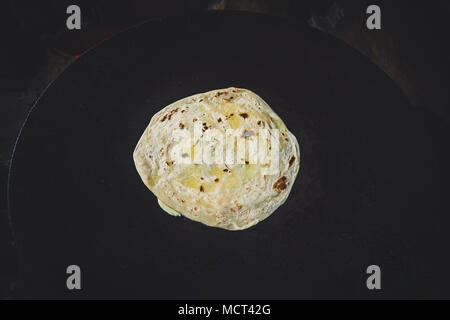 Paratha. Plain Wheaten Fladenbrot isoliert auf schwarzen Hintergrund der Ansicht von oben. Frische hausgemachte Fladenbrot auch als Fladenbrot, Chapati, Naan oder Tortilla bekannt Stockfoto