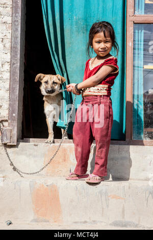 Portrait von kleinen Mädchen stehen auf Schritte mit gespeicherten Hund Hund Kette, Patan, Bagmati, Nepal Stockfoto