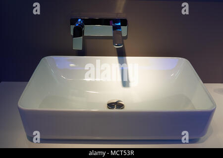 Weiß top Handwaschbecken und glänzendem Metall an der Wand montierten Mixer Stockfoto
