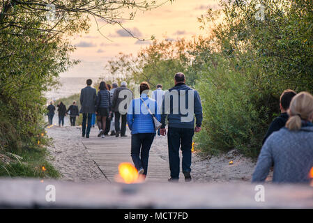 Romantische Lagerfeuer Nacht am Meer bei Sonnenuntergang. Leute versammeln um Nacht der alten Leuchten feiern. Wandern auf Holz weg am Meer Stockfoto