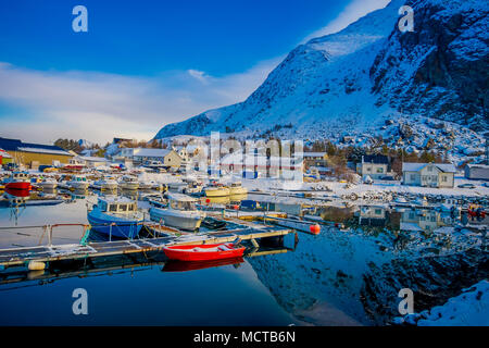 Henningsvær, Norwegen - 04 April, 2018: Im freien Blick auf die kleinen Fischerboote im Hafen mit einem Berg Spiegelbild im Wasser auf Lofoten Stockfoto