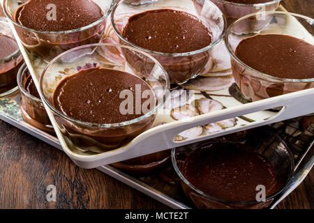 Hausgemachte Schokolade Puddings in Glas Tassen auf Holz- Oberfläche Stockfoto
