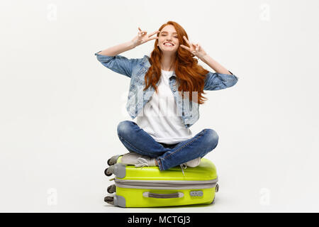 Travel Concept: junge lächelnde kaukasische Frau Standortwahl auf Koffer mit zwei Fingern. Auf weissem Hintergrund. Stockfoto