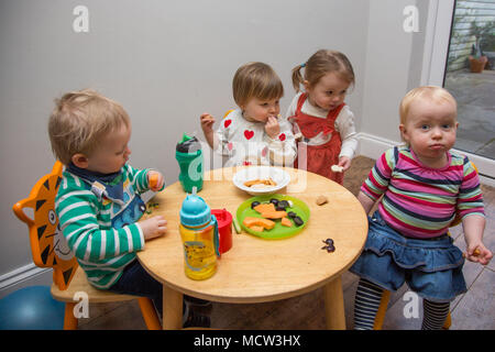 Babys und Kleinkinder mit einem Snack im Kindergarten, Großbritannien Stockfoto