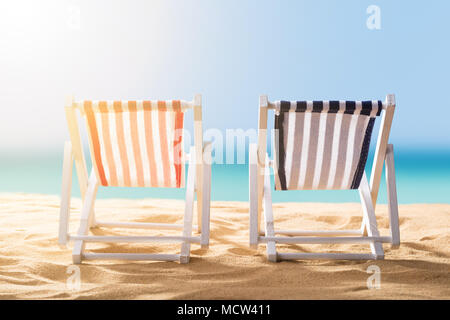 In der Nähe von zwei blau und rot gestreiften Liegestühle am Sandstrand Stockfoto