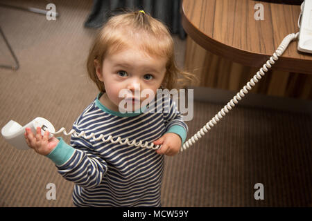18 Monate altes Kleinkind Mädchen spielen mit einem Haus-Telefon, Großbritannien Stockfoto