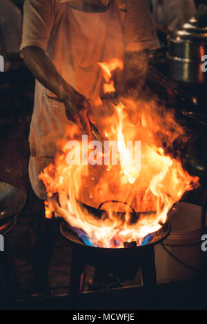 Nacht Bild eines Street Food Koch Kochen von Fleisch und Fisch in der Pfanne mit Feuer und Flammen unter. Chinatown, Bangkok, Thailand Stockfoto
