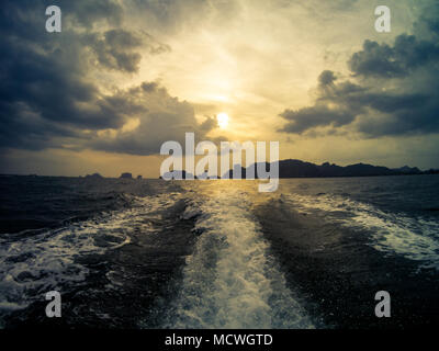 Blick auf den Sonnenuntergang von einem long tail Boot. Railay Beach auf dem Hintergrund. Krabi, Thailand. Stockfoto