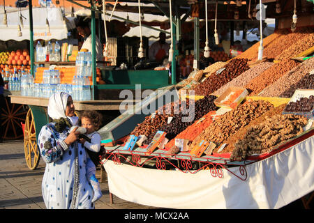 Frau, die ihr Kind auf dem Arm, getrocknet Datteln, Feigen, Aprikosen und andere Früchte auf dem Markt an der berühmten Place Jemaa el-Fnaa Platz in Marrakesch Stockfoto