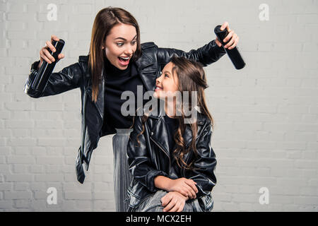 Modische Mutter Lachen und hält zwei haarsprays Stockfoto