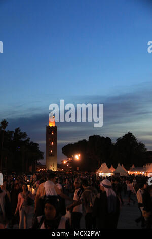 Masse von Menschen vor den Imbissständen und der marokkanischen Turm am Eingang zum berühmten Place Jemaa el-Fnaa Platz in Marrakesch, Marokko Stockfoto