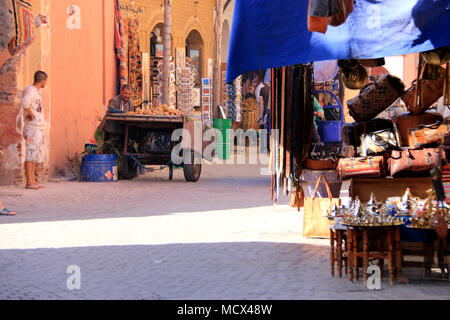 Marokkaner verkaufen frische Äpfel neben einigen Souvenir- und Textilien Speicher am Alten Souk in Medina in Marrakesch, Marokko Stockfoto