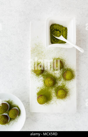 Hausgemachte matcha Schokolade Kugeln und Matcha Tee Pulver auf weißem Marmor Schneidebrett. Ansicht von oben. Stockfoto