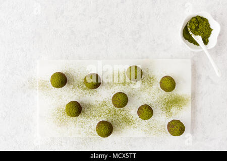 Hausgemachte Schokolade Trüffel auf weißem Marmor Schneidebrett bestäubt mit Green Matcha Tee Pulver. Ansicht von oben. Stockfoto