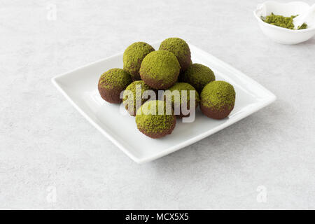 Hausgemachte Schokolade Trüffel bestäubt mit Green Matcha Pulver auf einem weißen Teller angeordnet. Stockfoto