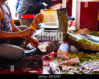 Fischer schneiden von Fisch auf einem ständigen Blade boti mit Hilfe eines hölzernen Stumpf in der indischen Fischmarkt in Kolkata Stockfoto