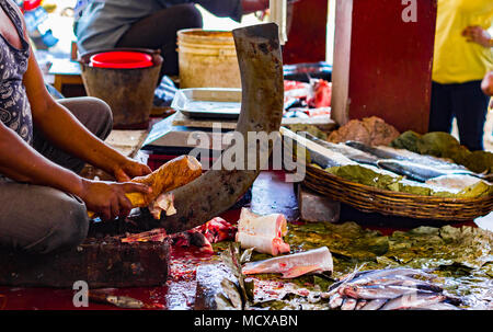 Fischer schneiden von Fisch auf einem ständigen Blade boti mit Hilfe eines hölzernen Stumpf in der indischen Fischmarkt in Kolkata Stockfoto