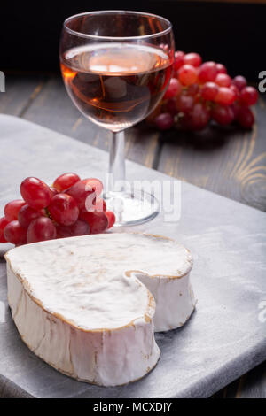 Französische Neufchatel herzförmige gealterte weiße Kuh Käse aus der Normandie mit Rose Wein serviert. Stockfoto