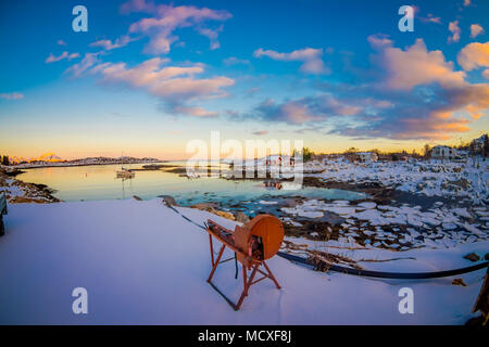 Im Hinblick auf metallische Struktur, die auf den Schnee in eine wunderschöne Aussicht auf den Sonnenuntergang mit kleinen und mittleren Stücke Eis hinter sich gelassen während der Ebbe auf einem zugefrorenen See in den Horizont Stockfoto