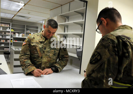 Spc. Jesse White, einem Fachmann in der 7409Th Truppe Medizinische Klinik zugeordnet, demonstriert den Prozess ein Soldat wird durch beim Besuch der TMC gehen. Weiß visits Kapitän Jeremy Tucker, der Apotheke Einsatzleiter, zu simulieren, die eine Verschreibung gefüllt. ARMEDCOM Soldaten zu 7212Th medizinische Unterstützung und 7409Th Truppe Medizinische Klinik zugeordnet unterstützt medizinische Soldat Bereitschaft Verarbeitung und Truppe Medizinische Klinik Operationen während ihrer Ausbildung am Fort McCoy, Wisconsin am März 1-15, 2018. Die erfolgreiche "Proof-of-Concept"-Programm durchgeführt wird, auf die mehrere Armee Rese Stockfoto