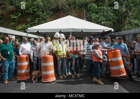 Utuado, Puerto Rico, März 13, 2018 - Mitglieder der Regierung, gemeinsam mit Anwohnern und Arbeitern, Sicherheit Fässer entfernen im Rahmen der offiziellen Eröffnung der neuen Brücke am Río Abajo. Dank der Bemühungen der Regierung von Puerto Rico, FEMA und anderen Partnern, die Gemeinschaft kann wieder normal gehen nach der letzten Brücke wegen Hurricane María zusammengebrochen. Stockfoto