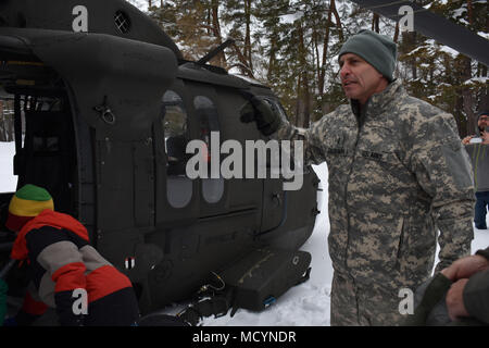 New York Army National Guard Chief Warrant Officer 3 Johannes Delsignore, 3 Bataillon zugeordnet, 142 Luftfahrt, spricht mit lokalen Familien über die UH-60 Black Hawk, und was sein Gerät funktioniert, in Cooperstown, NEW YORK, 3. März, 2018. Einheit Mitglieder waren die Durchführung einer Übung mit einer Armee Finden zivilen Angelegenheiten unternehmen und Anwohner hatten sich versammelt, um die Hubschrauber zu sehen. Delsignore sprach mit der Familie darüber, wie die National Guard hilft der Gemeinschaft durch die Reaktion auf Notfälle und der Unterstützung von anderen Einheiten während eingesetzt. (N.Y. Nationalgarde Foto von SPC. Andrew Valenza) Stockfoto