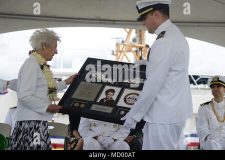 Lt. Colin McKee, kommandierender Offizier, der U.S. Coast Guard Cutter Joseph Gerczak (WPC-1126) vorgestellt, ein Geschenk zu "Tante" Stella Gerczak, die jüngste Schwester, Namensgeber der Cutter, die während der Inbetriebnahme Zeremonie auf Basis Honolulu, 9. März 2018. Tante Stella war Sponsor des Schiffes und von Philadelphia gereist, um die Zeremonie zu Ehren ihres Bruders zu besuchen. (U.S. Coast Guard Foto von Petty Officer 3. Klasse Amanda Poudret/Freigegeben) Stockfoto