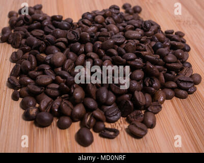 Frisch geröstete Kaffeebohnen closeup auf natürliche Holzoberfläche Ansicht von oben. Stockfoto